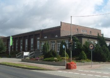 Backsteinbau des BASF-Kulturhauses in Schwarzheide mit Treppe, Grünanlage und Straße im Vordergrund