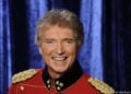 Peter Orloff in roter Uniformjacke mit goldenen Schulterstücken vor einem blauen Vorhang