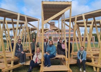 Menschen sitzen in überdachten Holzboxen auf der Freifläche an der Briesker Straße in Senftenberg
