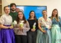 Fünf Studierende, einige in sorbischer Tracht, mit Zuckertüten und ihre Dozentin vor einem Bildschirm mit BTU-Logo