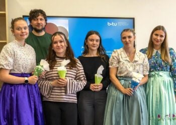 Fünf Studierende, einige in sorbischer Tracht, mit Zuckertüten und ihre Dozentin vor einem Bildschirm mit BTU-Logo