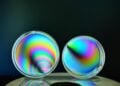 Zwei Petrischalen aus Polystyrol leuchten zwischen gekreuzten Polarisationsfiltern in Regenbogenfarben