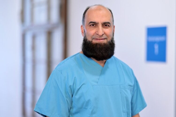 Chefarzt Dr. Ahmad Oyais in hellblauer OP-Kleidung auf einem Klinikflur