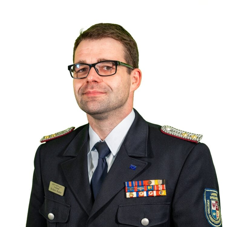 Robert Buder in Feuerwehr-Dienstuniform mit Brille vor weißem Hintergrund