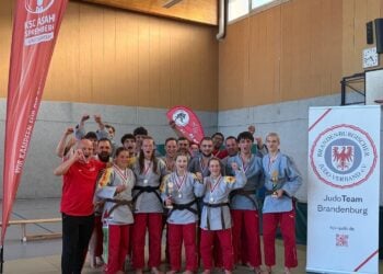 Die Frauen- und Männerteams des KSC ASAHI Spremberg jubeln mit Medaillen und Pokalen nach den Finals der Judo-Landesliga