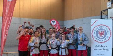 Die Frauen- und Männerteams des KSC ASAHI Spremberg jubeln mit Medaillen und Pokalen nach den Finals der Judo-Landesliga