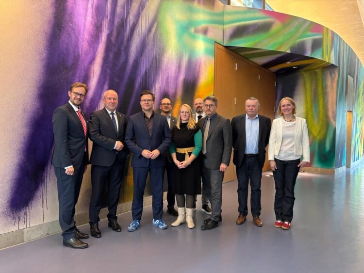 Die Delegation der Lausitzrunde mit Bundesumweltminister Carsten Schneider vor einer bunten Wandmalerei im Ministerium in Berlin