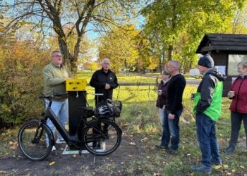 Mehrere Menschen stehen an einer gelben Reparatursäule, an der ein E-Bike eingehängt ist