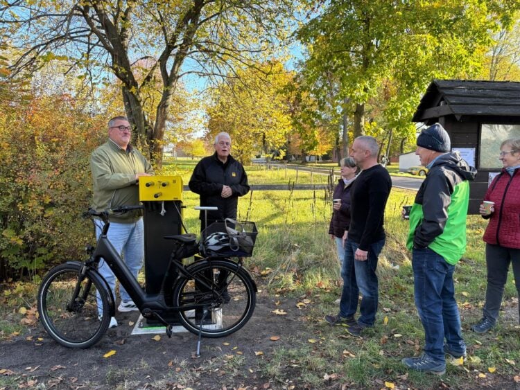 Mehrere Menschen stehen an einer gelben Reparatursäule, an der ein E-Bike eingehängt ist