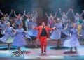 Szenenfoto aus Messeschlager Gisela mit Heiko Walter im roten Anzug, Tänzerinnen in blauen Kleidern und Ensemble