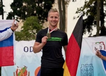 Tom Gehlert mit Medaille auf dem Siegerpodest beim Odessos-Cup in Varna, daneben eine Deutschlandfahne