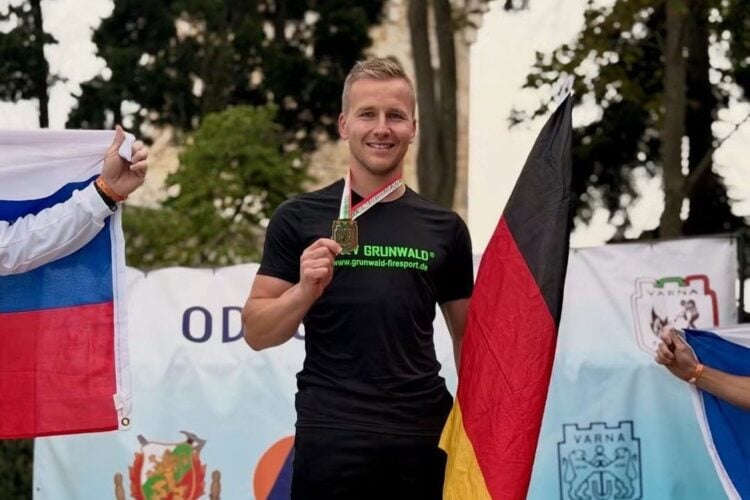 Tom Gehlert mit Medaille auf dem Siegerpodest beim Odessos-Cup in Varna, daneben eine Deutschlandfahne