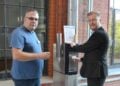 Zwei Männer mit Bechern an einem neuen Trinkwasserspender im Kreishaus in Forst (Lausitz)