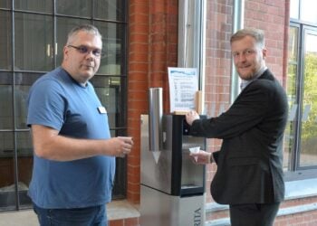 Zwei Männer mit Bechern an einem neuen Trinkwasserspender im Kreishaus in Forst (Lausitz)