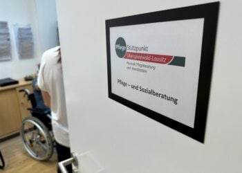Tür des Pflegestützpunktes Oberspreewald-Lausitz mit Schild Pflege- und Sozialberatung, dahinter ein Beratungsraum mit Rollstuhl