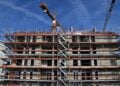 Rohbau eines Mehrfamilienhauses mit Gerüst und Baukränen