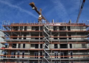 Rohbau eines Mehrfamilienhauses mit Gerüst und Baukränen