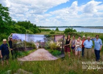 Wortwechsel in Altdöbern: Menschen halten in einer Landschaft am See ein großes Bildbanner