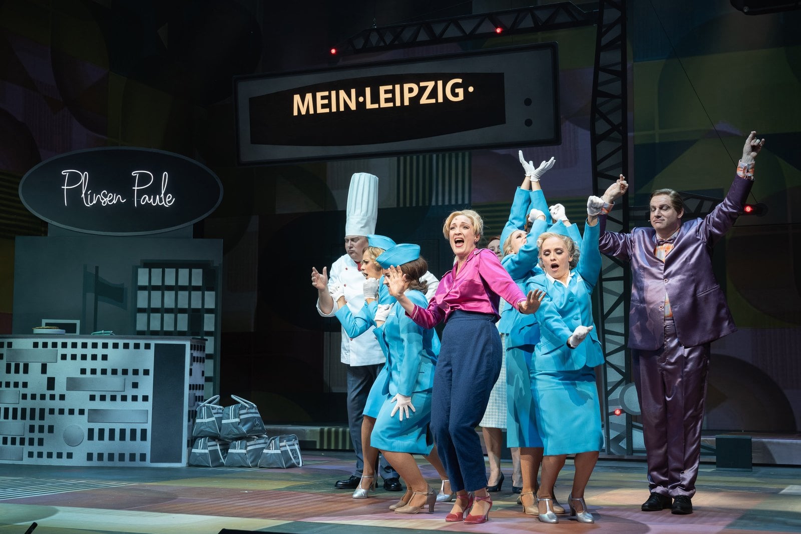 Szenenfoto aus der Operette Messeschlager Gisela mit Darstellerinnen in blauen Kostümen vor einer Leipzig-Kulisse