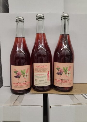 Drei Flaschen Wolkenløs Sparkling Tea Rosé vor Kartons