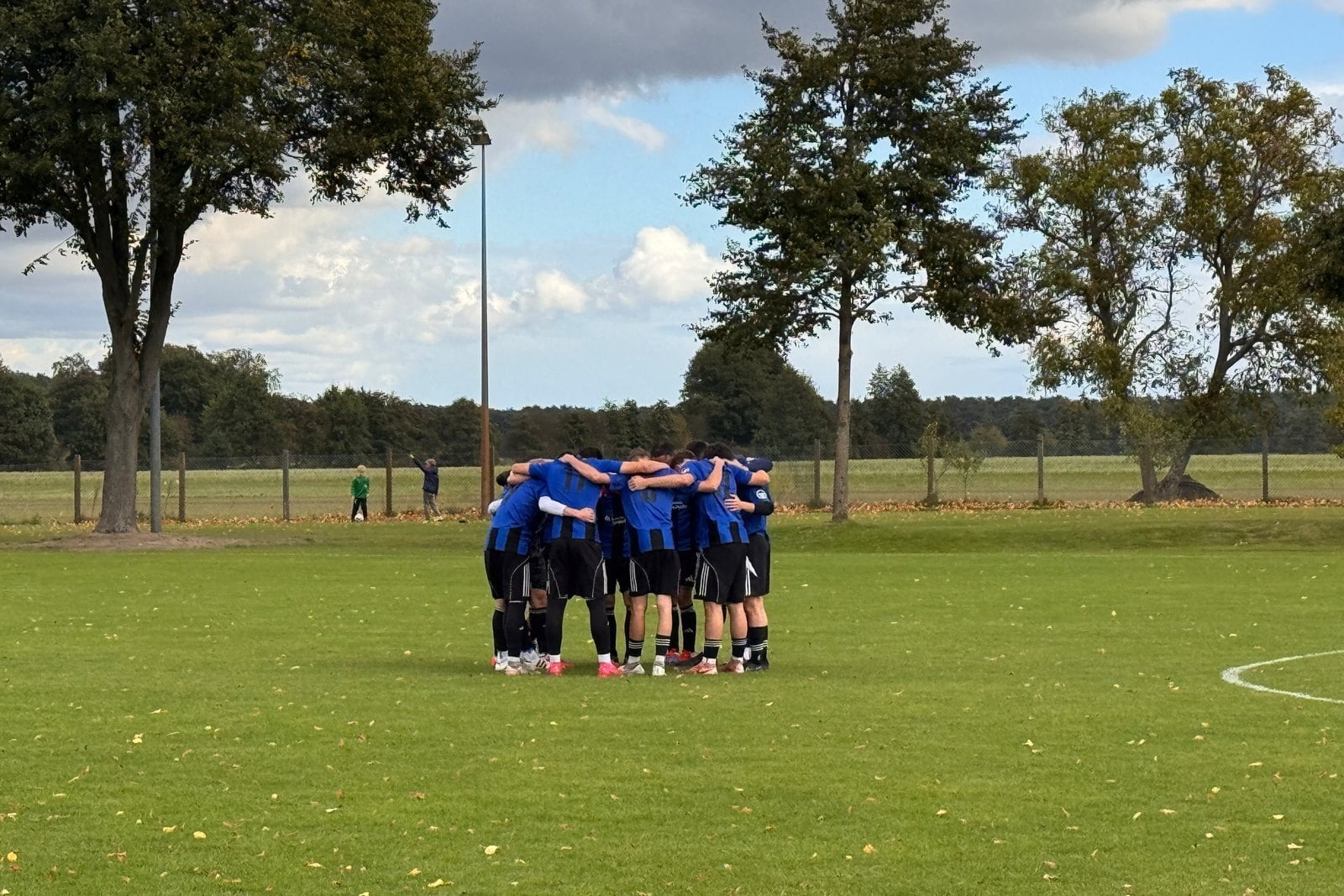 Fußballer der SG Dissenchen/Haasow in blauen Trikots stehen auf dem Platz im Kreis zusammen