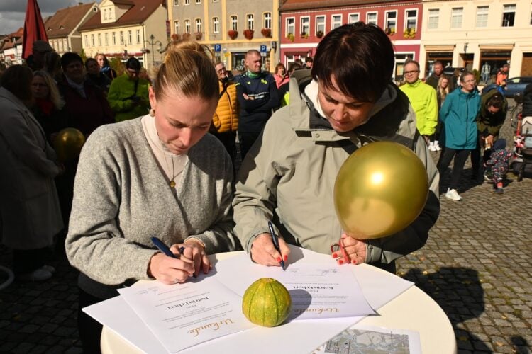 Sternenkinderlauf in Lübbenau: Amy Kullick und Katrin Erbert unterzeichnen auf dem Kirchplatz eine Urkunde