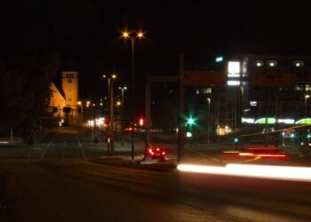 Nahezu leere Kreuzung am Bahnhof Cottbus bei Nacht mit Straßenlaternen und Lichtspuren eines Autos