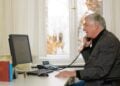 Ein ehrenamtlicher Mitarbeiter der Telefonseelsorge telefoniert an einem Schreibtisch mit Computer