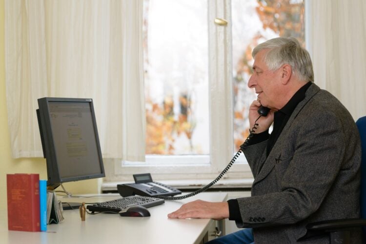 Ein ehrenamtlicher Mitarbeiter der Telefonseelsorge telefoniert an einem Schreibtisch mit Computer