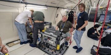 Forscher arbeiten in der Kabine eines Parabelflugzeugs an einem Versuchsgestell mit Messtechnik