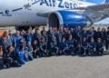 Große Gruppe in blauen Overalls vor einem Flugzeug mit der Aufschrift Air Zero G