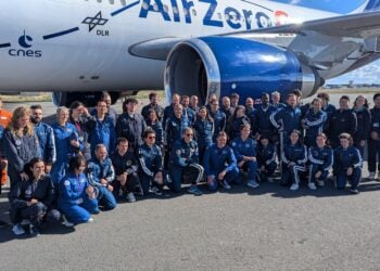 Große Gruppe in blauen Overalls vor einem Flugzeug mit der Aufschrift Air Zero G
