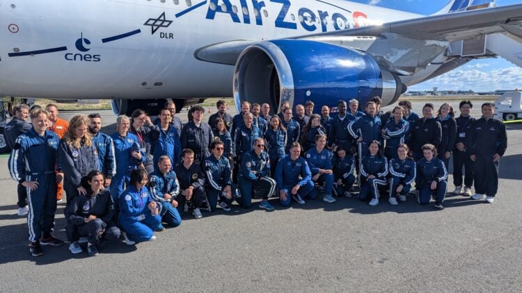 Große Gruppe in blauen Overalls vor einem Flugzeug mit der Aufschrift Air Zero G