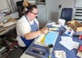 Teilnehmerin mit Kopfhörern bemalt in einer Werkstatt eine Platte für ein Puppentheater