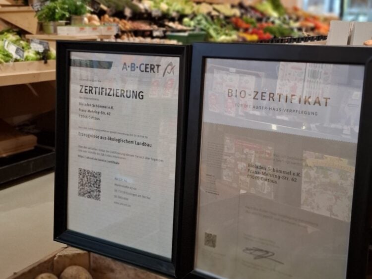 Gerahmte Bio-Zertifikate im Bioladen Schömmel in Cottbus, dahinter Regale mit Obst und Gemüse