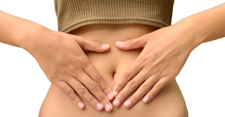 Eine Frau legt beide Hände in Herzform auf ihren Bauch