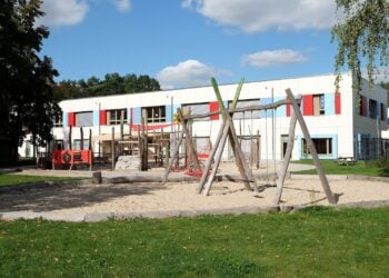 Betreuungsstufe Symbolbild: leerer Spielplatz mit Holzgerüsten vor einem Kita-Gebäude in Königs Wusterhausen