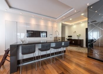 Moderne Küche mit Kochinsel, Barhockern und mehreren Einbaustrahlern in einer abgehängten Decke
