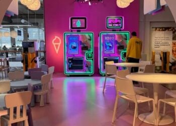 Zwei beleuchtete Softeis-Automaten Robo Ice Cream an einer pinken Wand in einem Restaurantbereich