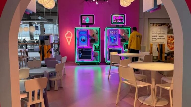 Zwei beleuchtete Softeis-Automaten Robo Ice Cream an einer pinken Wand in einem Restaurantbereich