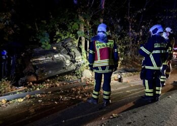 Feuerwehrleute an dem auf der Seite liegenden Unfallwagen in Bohrau
