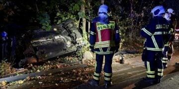 Feuerwehrleute an dem auf der Seite liegenden Unfallwagen in Bohrau