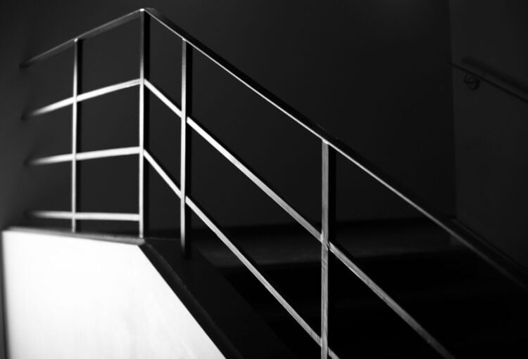 Schwarz-Weiß-Aufnahme einer Treppe mit schlichtem Stahlgeländer