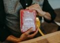 Hände halten eine rote Geschenkschachtel mit Zuckerstangen
