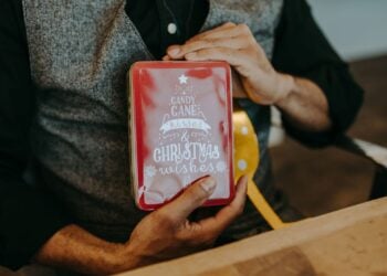 Hände halten eine rote Geschenkschachtel mit Zuckerstangen