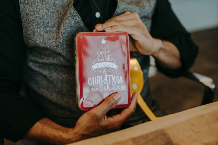 Hände halten eine rote Geschenkschachtel mit Zuckerstangen